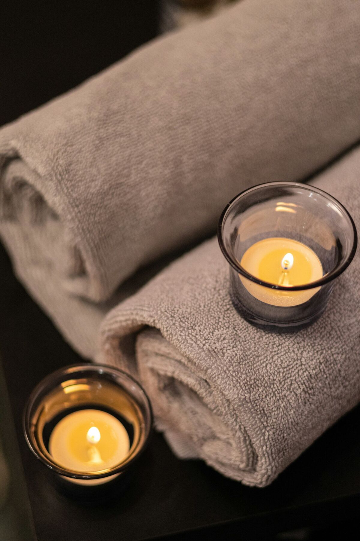 Rolled towels beside two lit candles